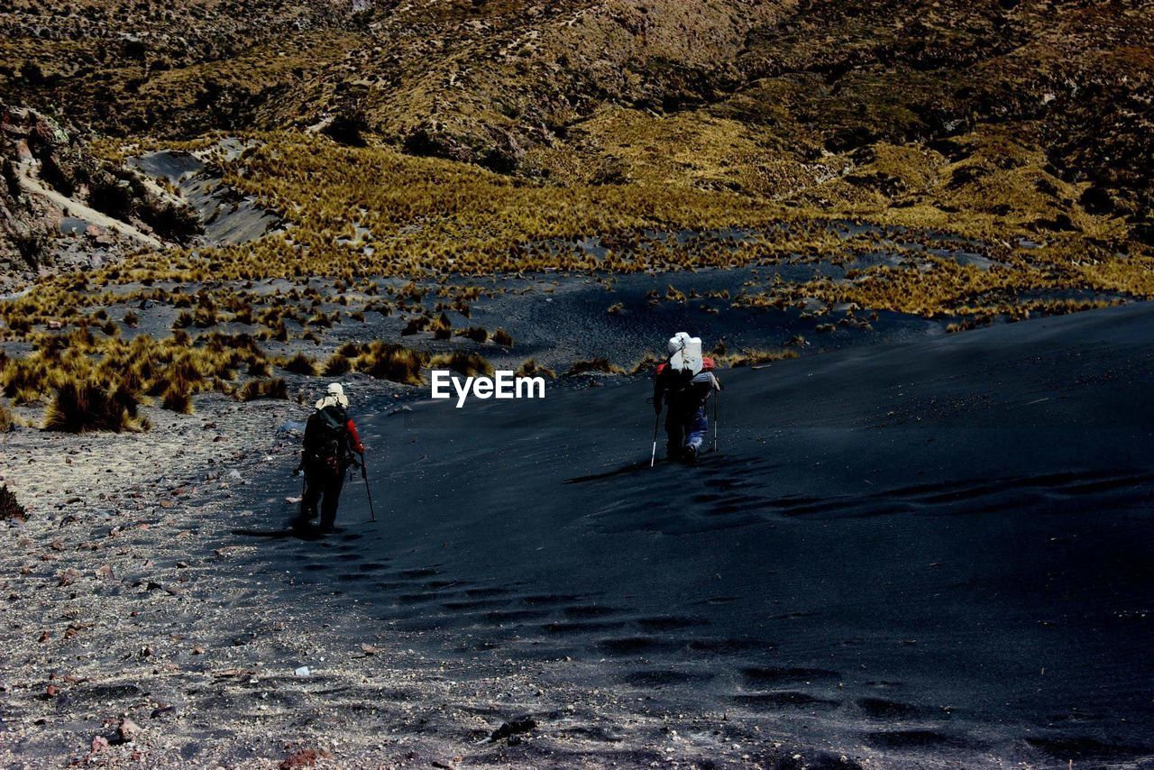 Rear view of people walking on field against mountain