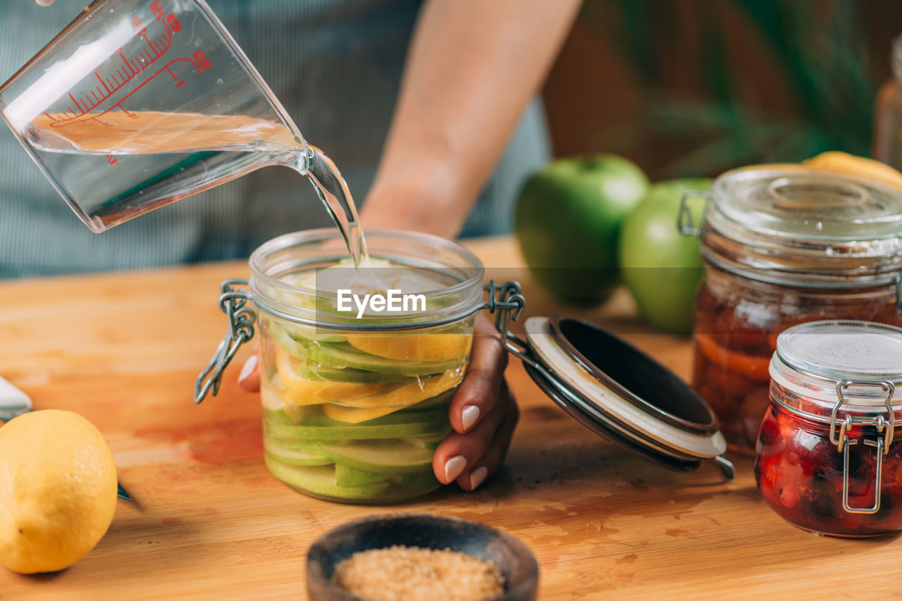 CLOSE-UP OF HAND HOLDING DRINK IN JAR