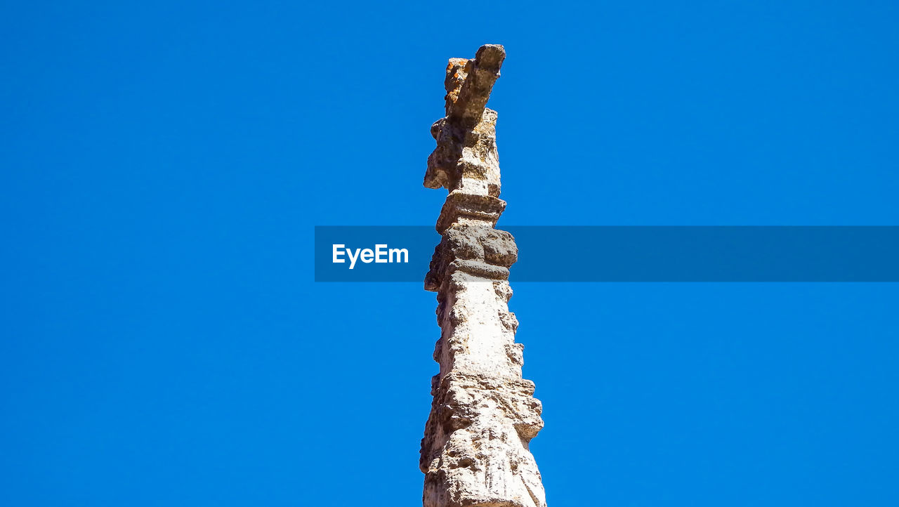 Low angle view of tree trunk against clear blue sky