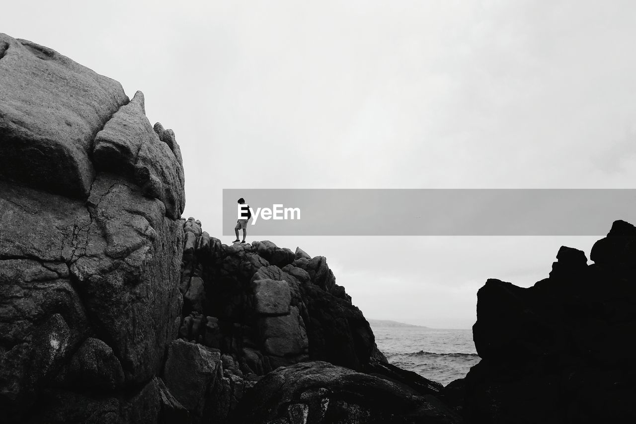 Low angle view of man standing on cliff against clear sky