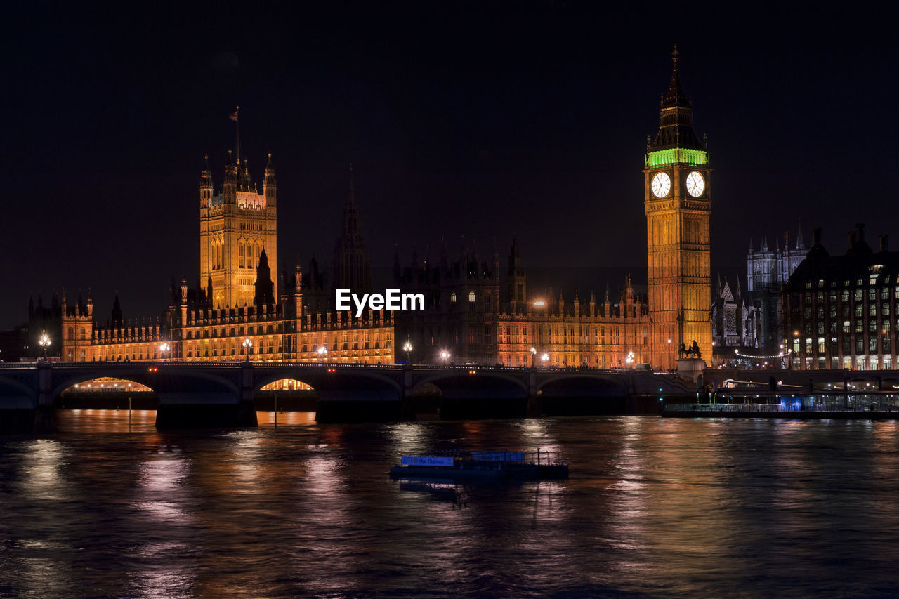 ILLUMINATED BUILDINGS IN CITY AT WATERFRONT