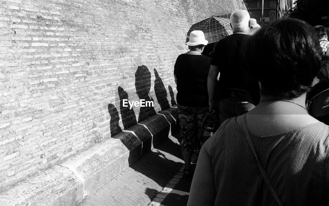 Rear view of people walking by wall