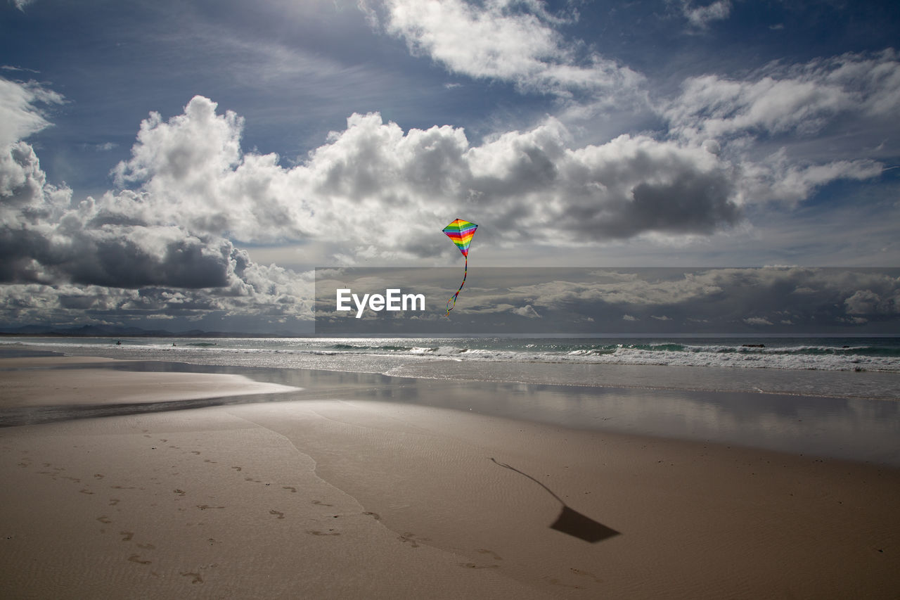 Scenic view of beach against sky and kite flying