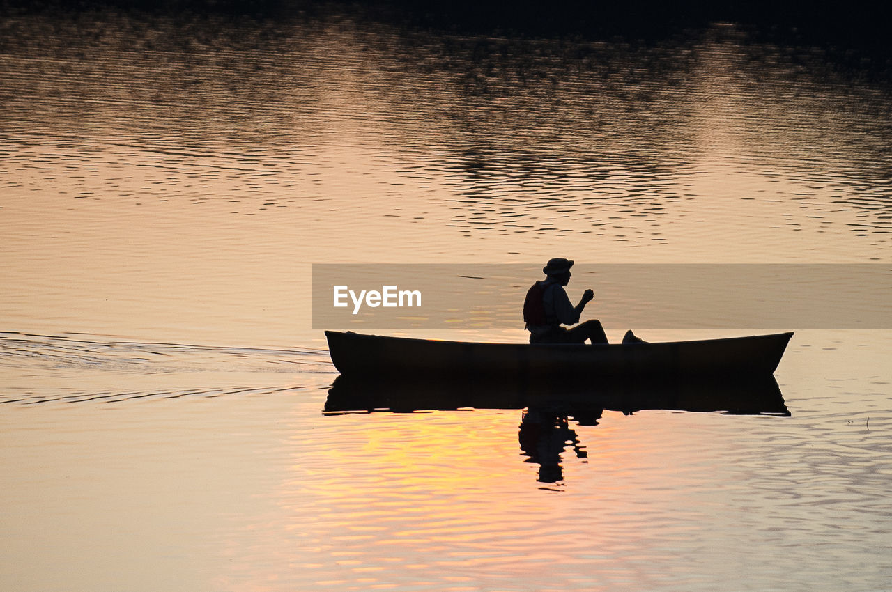 Silhouette person sitting on boat on lake