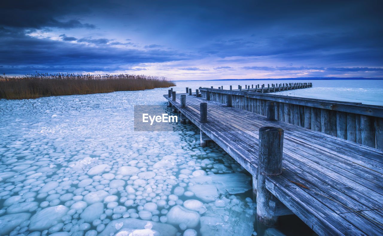 SCENIC VIEW OF PIER OVER SNOW COVERED LANDSCAPE AGAINST SKY