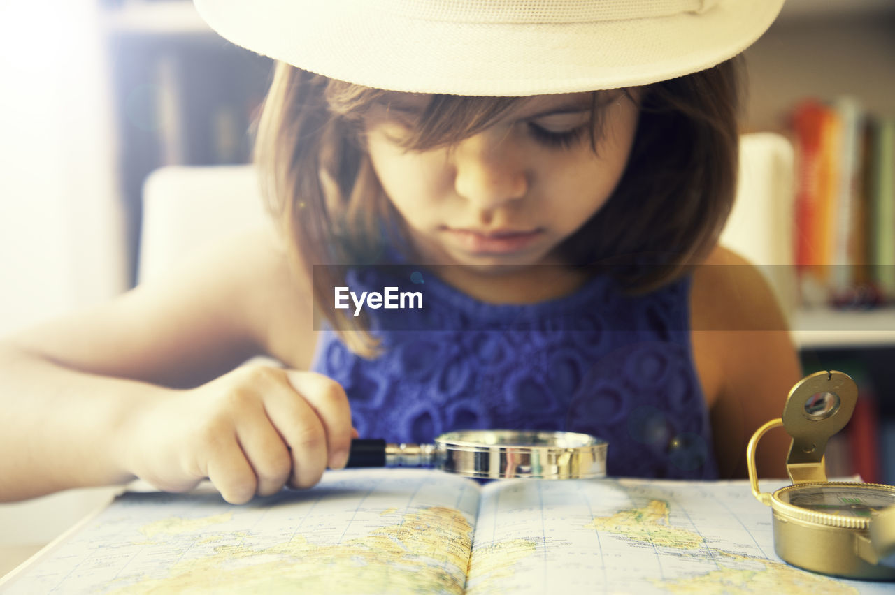 Close-up of girl looking map with magnifying glass