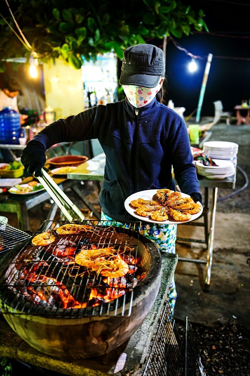 Woman grilling prawns on barbecue