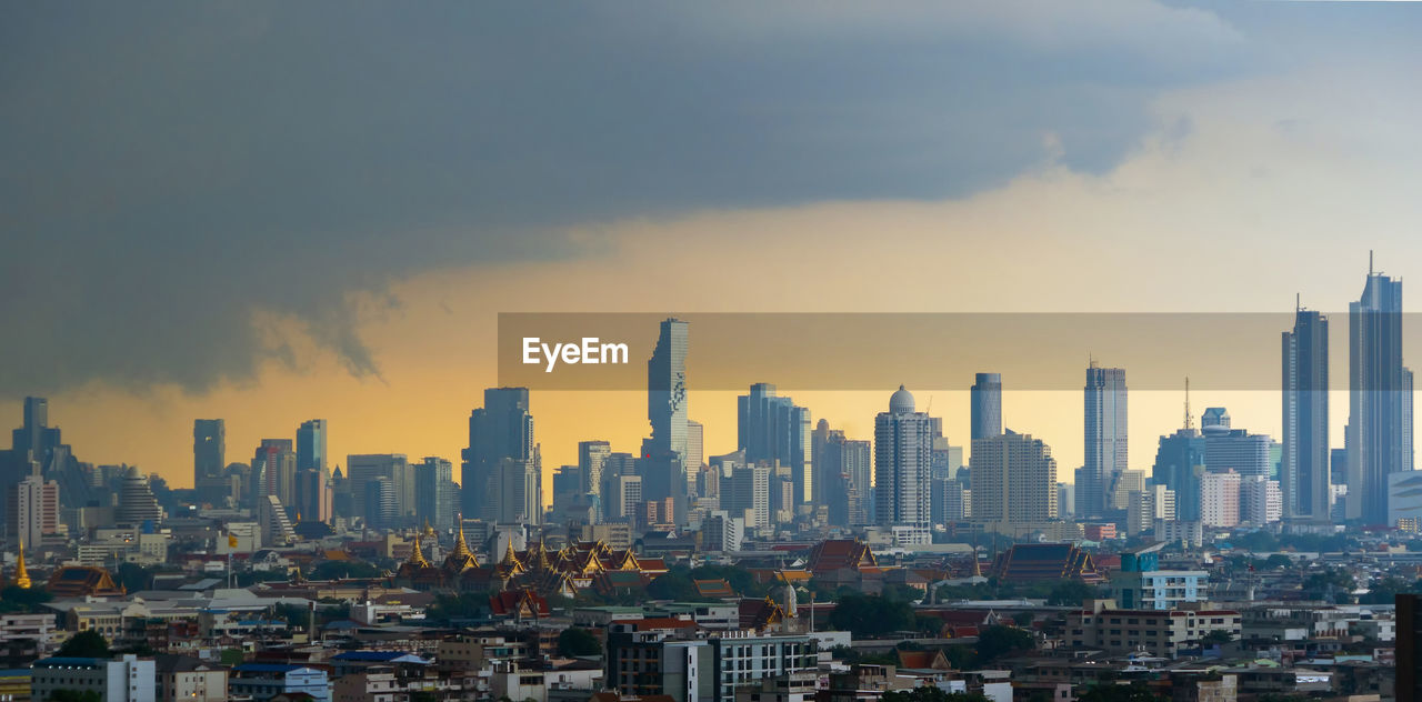 Modern buildings in city against sky during sunset