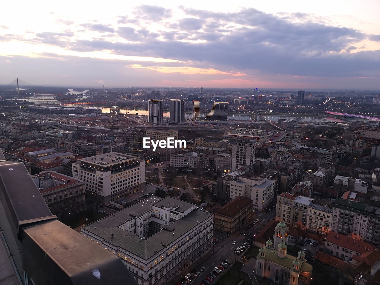 HIGH ANGLE VIEW OF BUILDINGS IN CITY AGAINST CLOUDY SKY