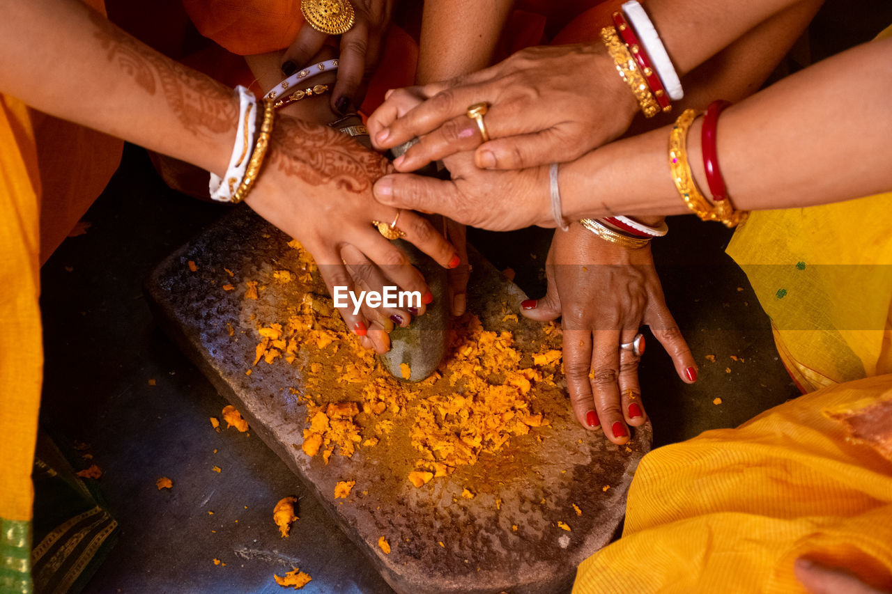 High angle view of women crushing turmeric on stone