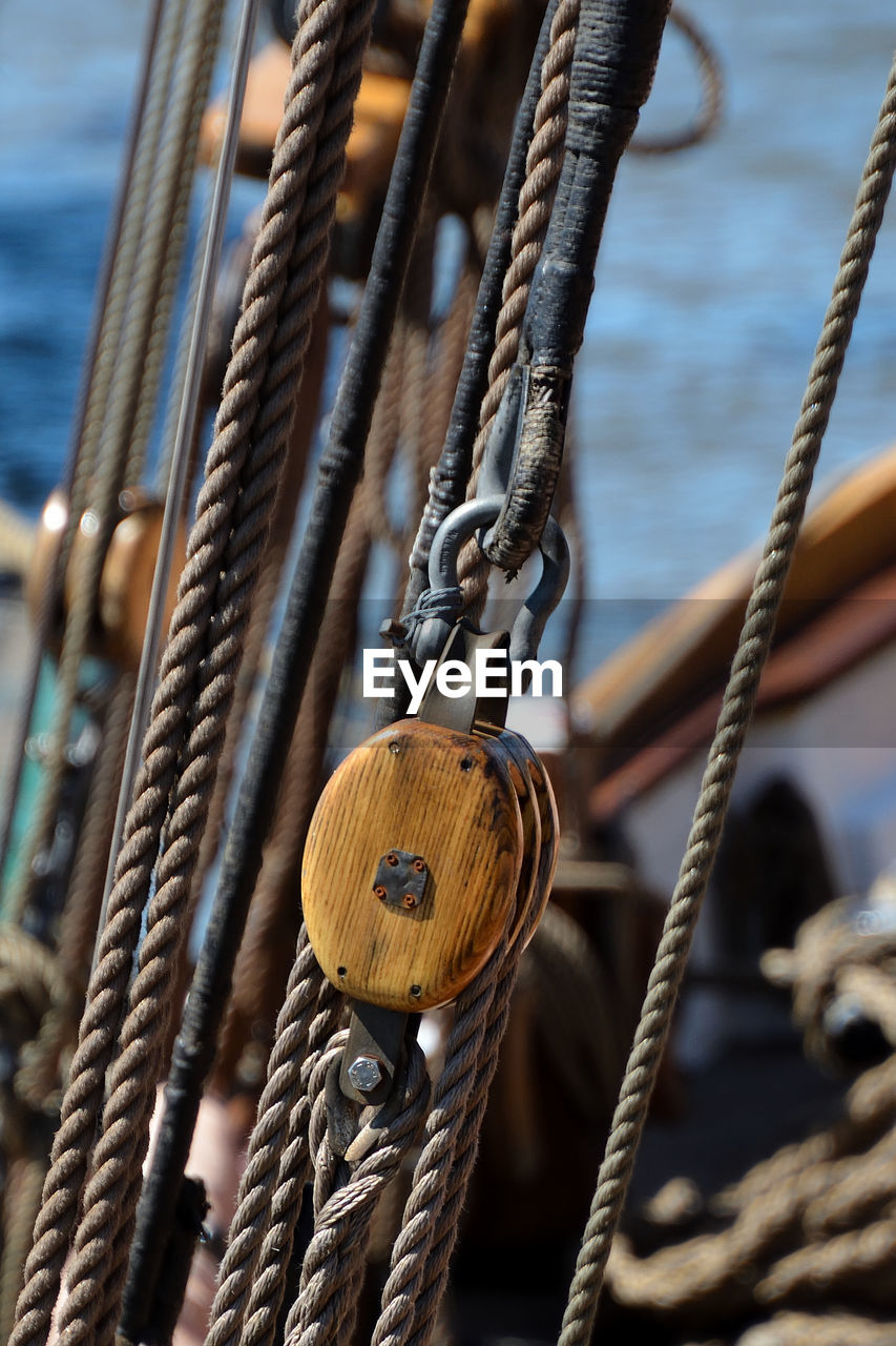 CLOSE-UP OF ROPE TIED TO BOLLARD ON METAL