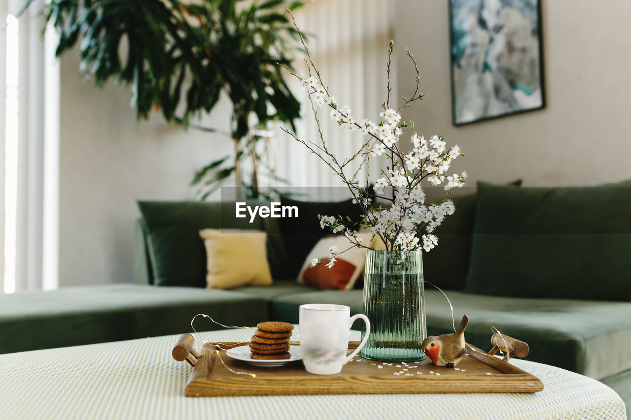 Home interior. cookies, coffee. apple tree color has flown, bird. blurred background