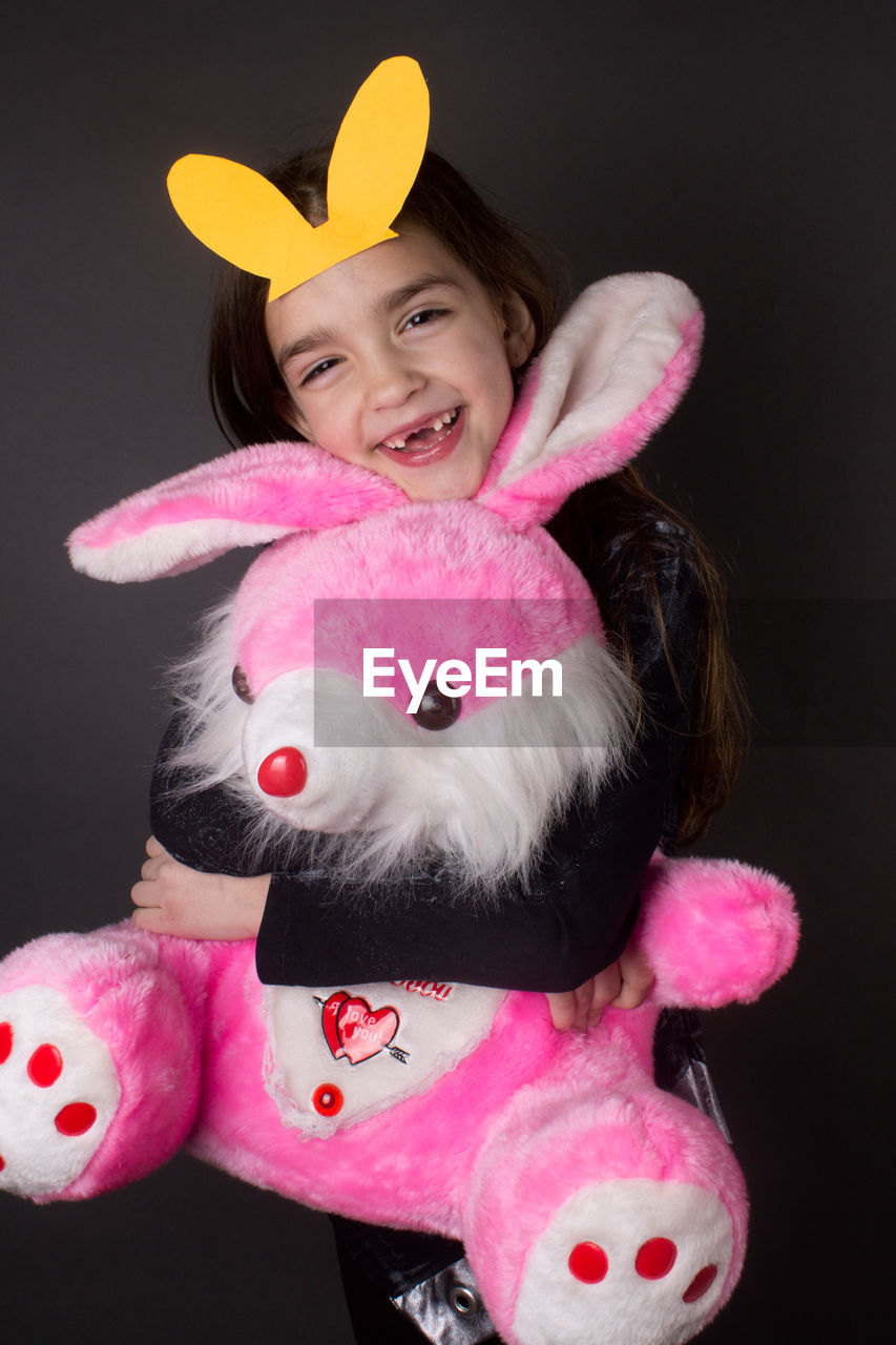 Girl embracing eater bunny stuffed toy against gray background