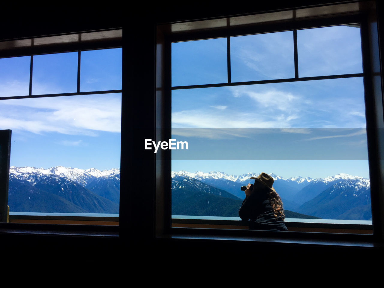 Rear view of woman against sky seen through window