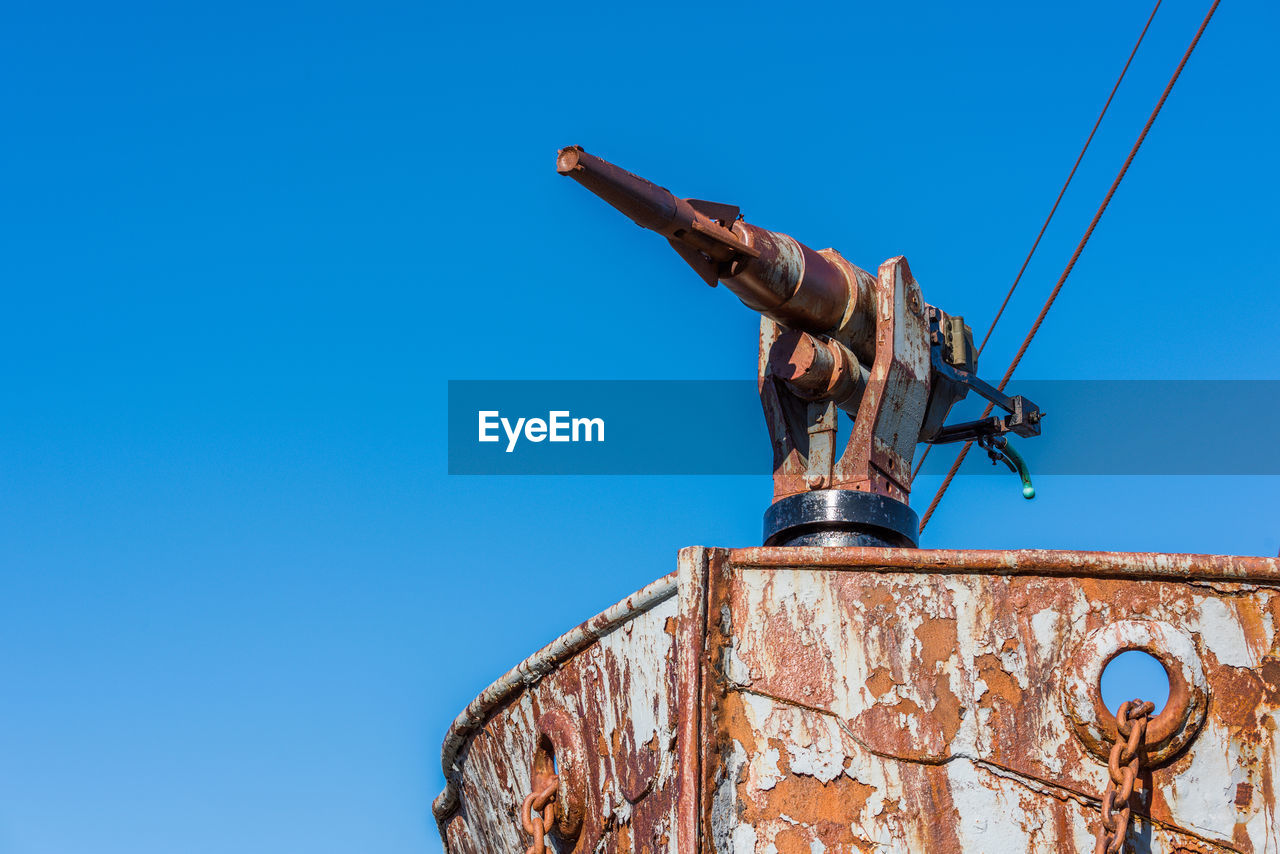 Low angle view of abandoned ship against clear blue sky