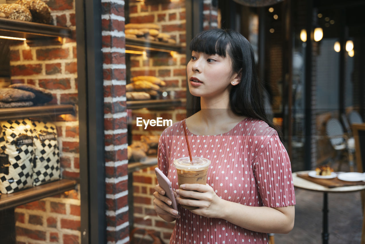 WOMAN LOOKING AWAY WHILE STANDING BY STORE