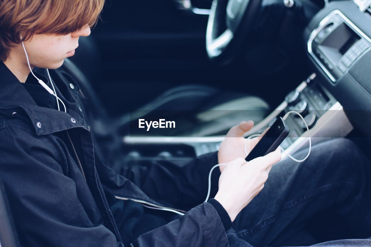 High angle view of teenage boy listening music while sitting in car