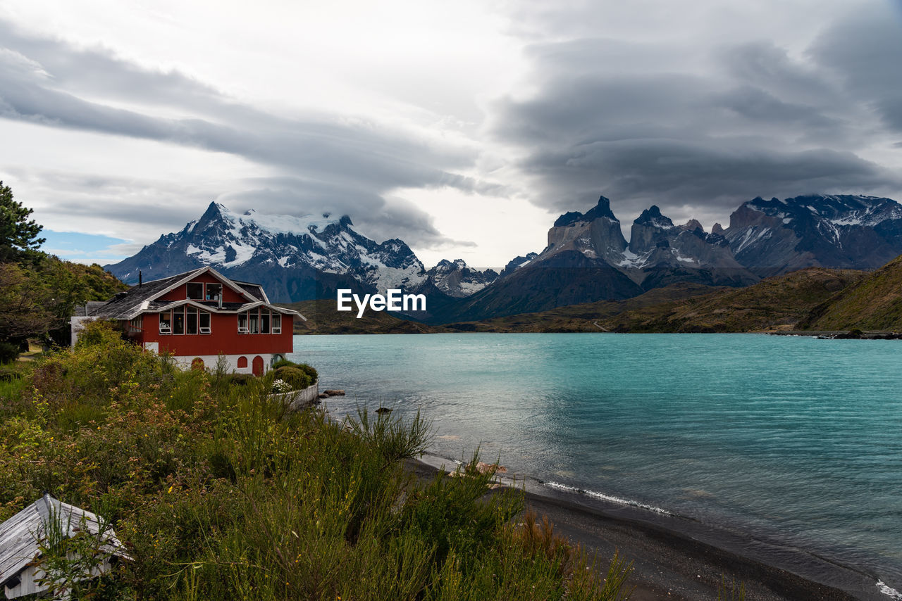 Scenic view of lake by building and mountains against sky