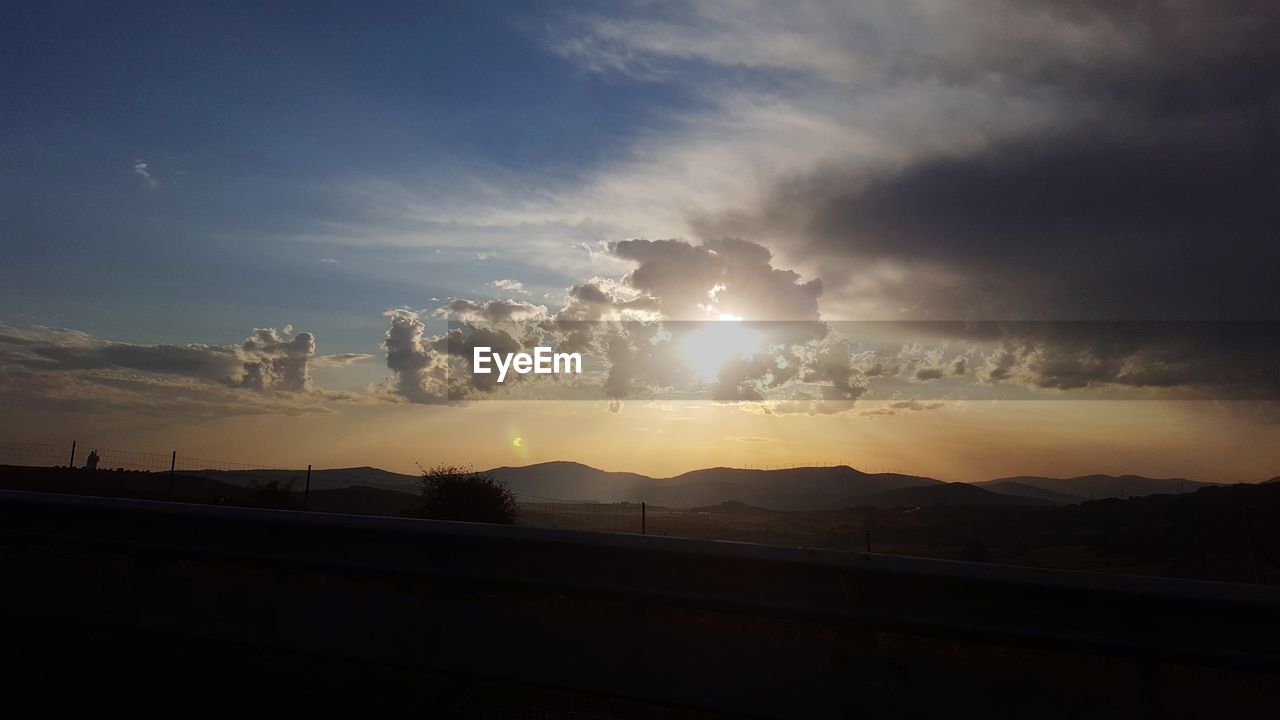 SCENIC VIEW OF SILHOUETTE MOUNTAINS AGAINST SKY AT SUNSET