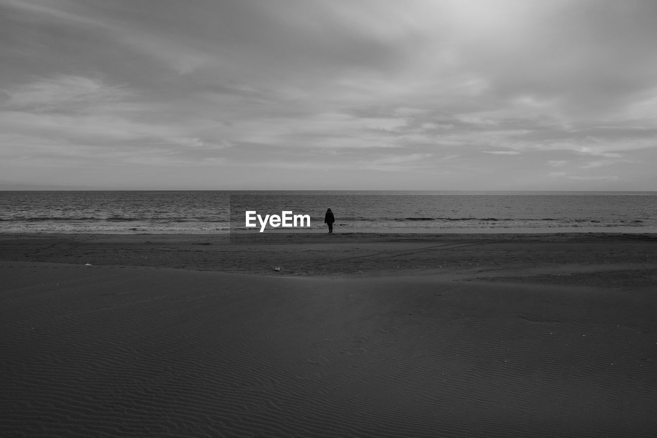 MAN ON BEACH AGAINST SKY