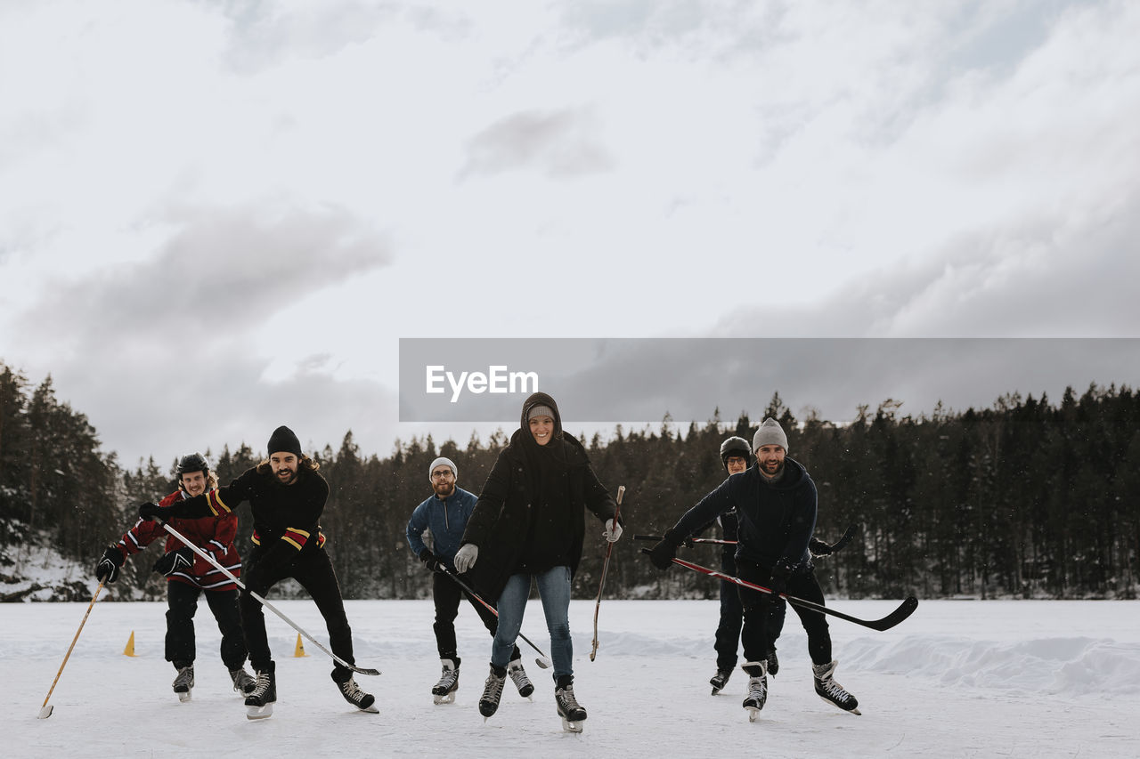 Friends playing hockey on frozen lake