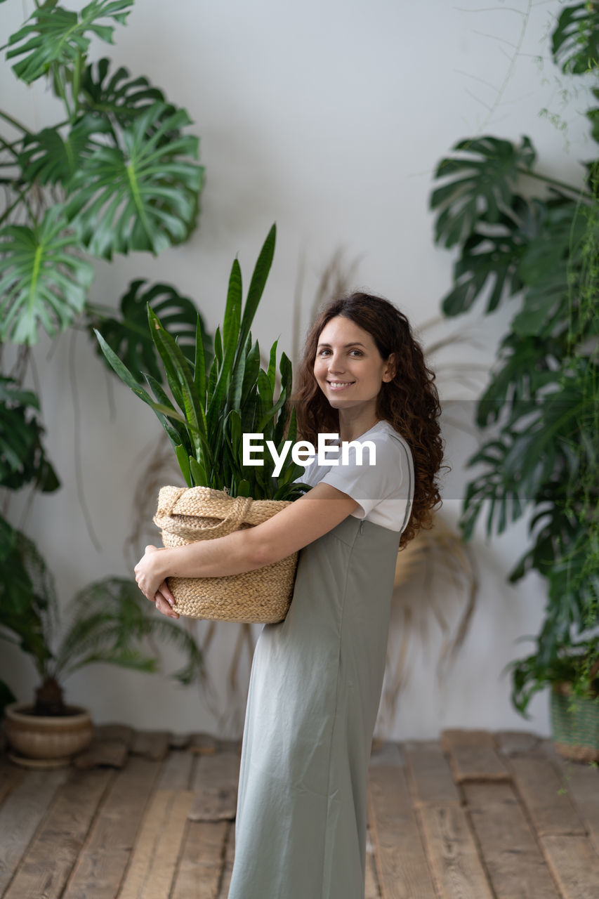 Love for plants. happy woman hold pot with sansevieria houseplant smiling in indoor garden at home