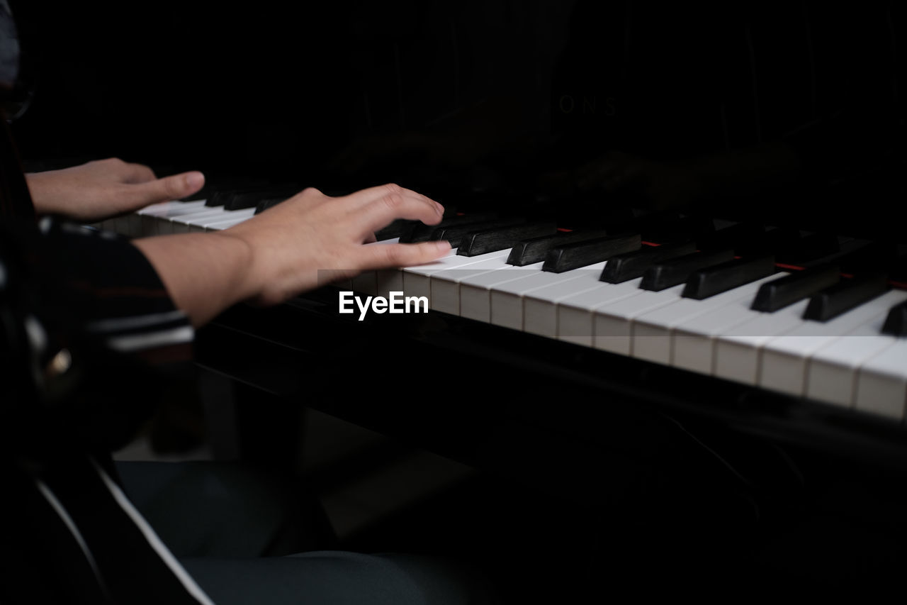 Cropped hand of man playing piano