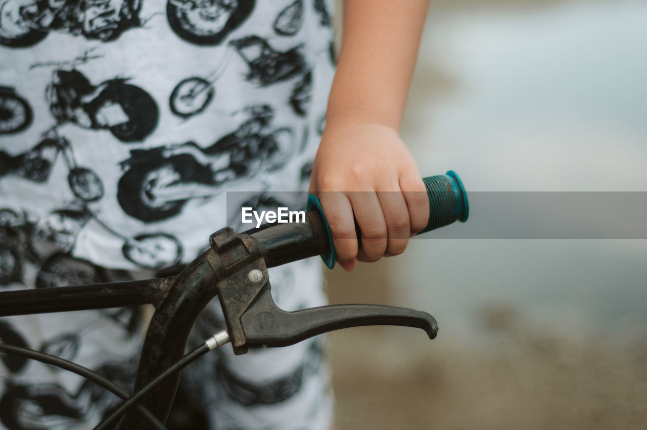 Midsection of child holding bicycle