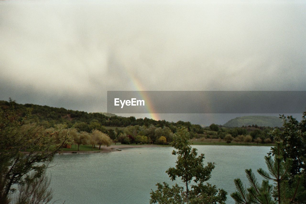 SCENIC VIEW OF RAINBOW OVER CALM LAKE