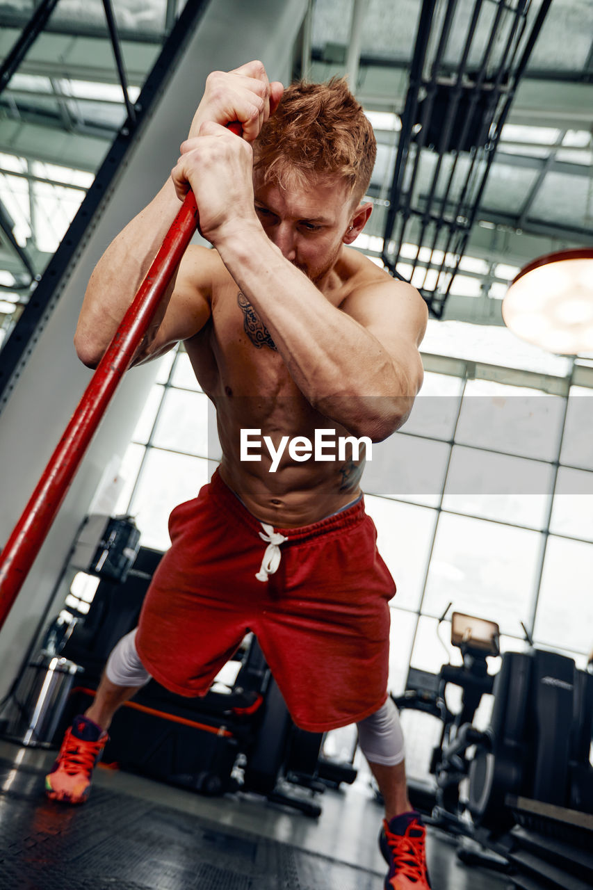 Low angle view of shirtless man exercising in gym