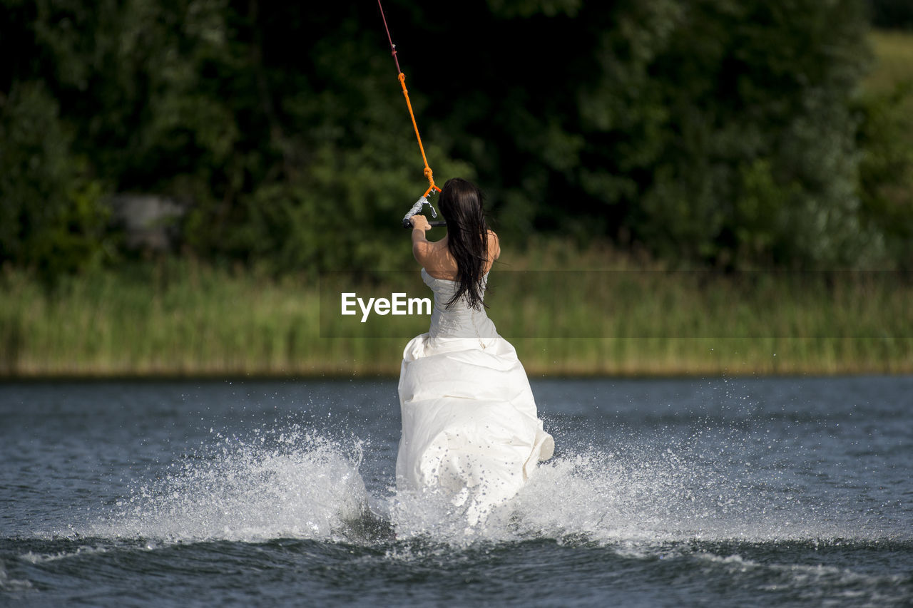 Woman wearing dress while kiteboarding in lake