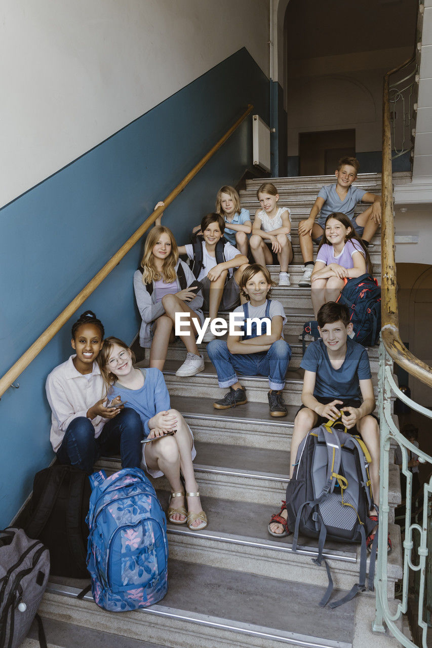 Portrait of smiling multiracial male and female students sitting on school staircase