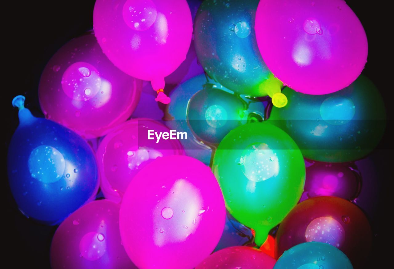 CLOSE-UP OF MULTI COLORED BALLOONS OVER WATER