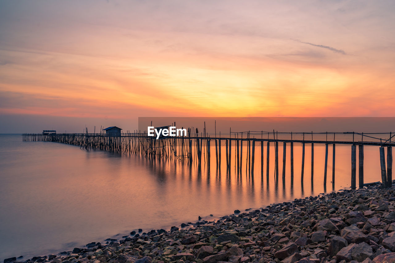 PIER ON SEA AGAINST ORANGE SKY