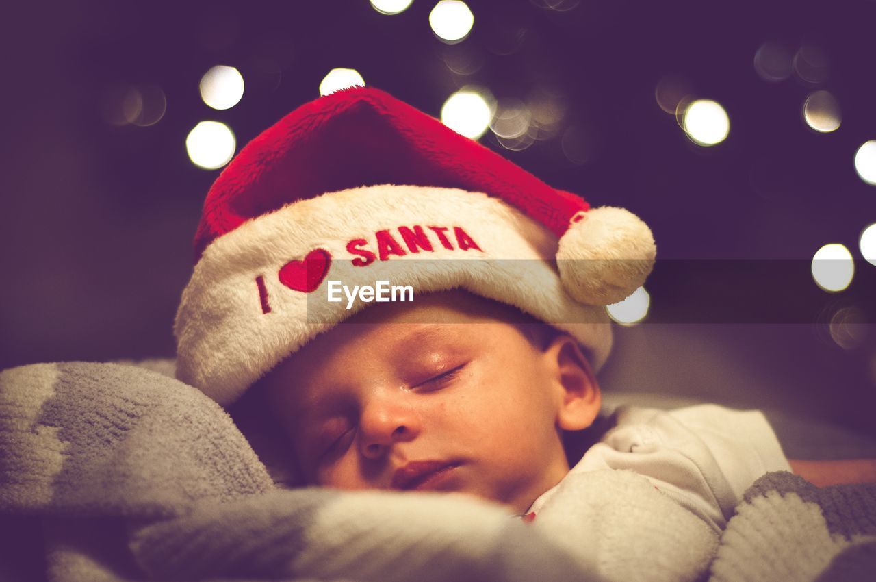 PORTRAIT OF CUTE BOY SLEEPING IN ILLUMINATED CHRISTMAS