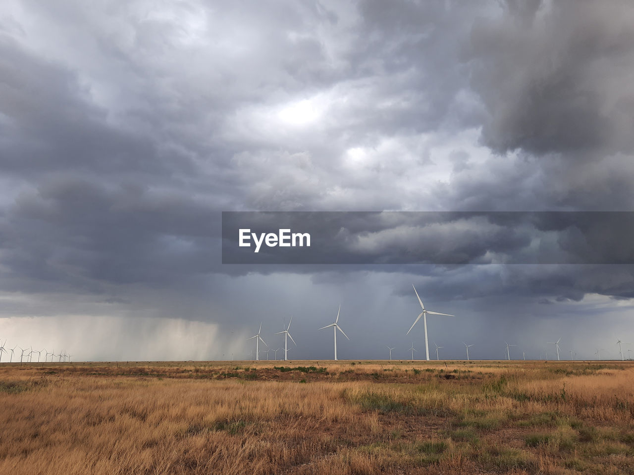 Scenic view of field with windmills against cloudy sky