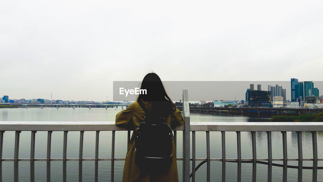 Rear view of woman looking at cityscape against sky