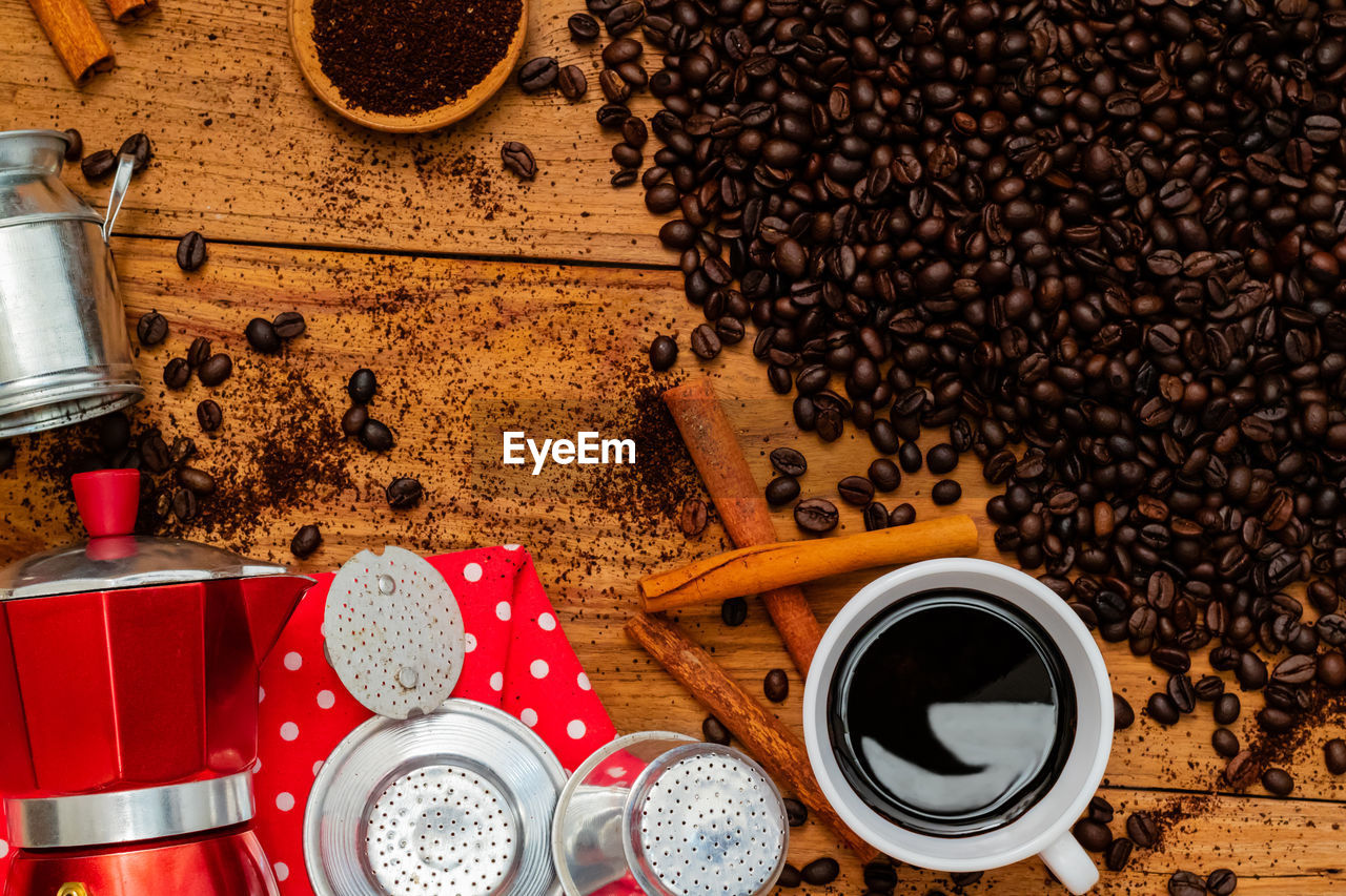 Black coffee in cup, coffee beans and ingredient on wooden table.top view.