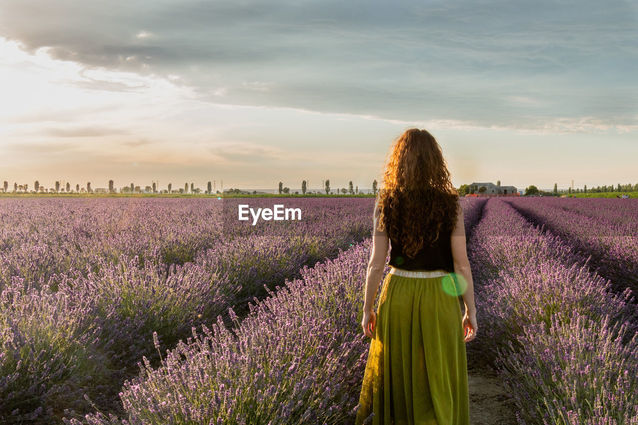 Rear view of woman walking on land against sky