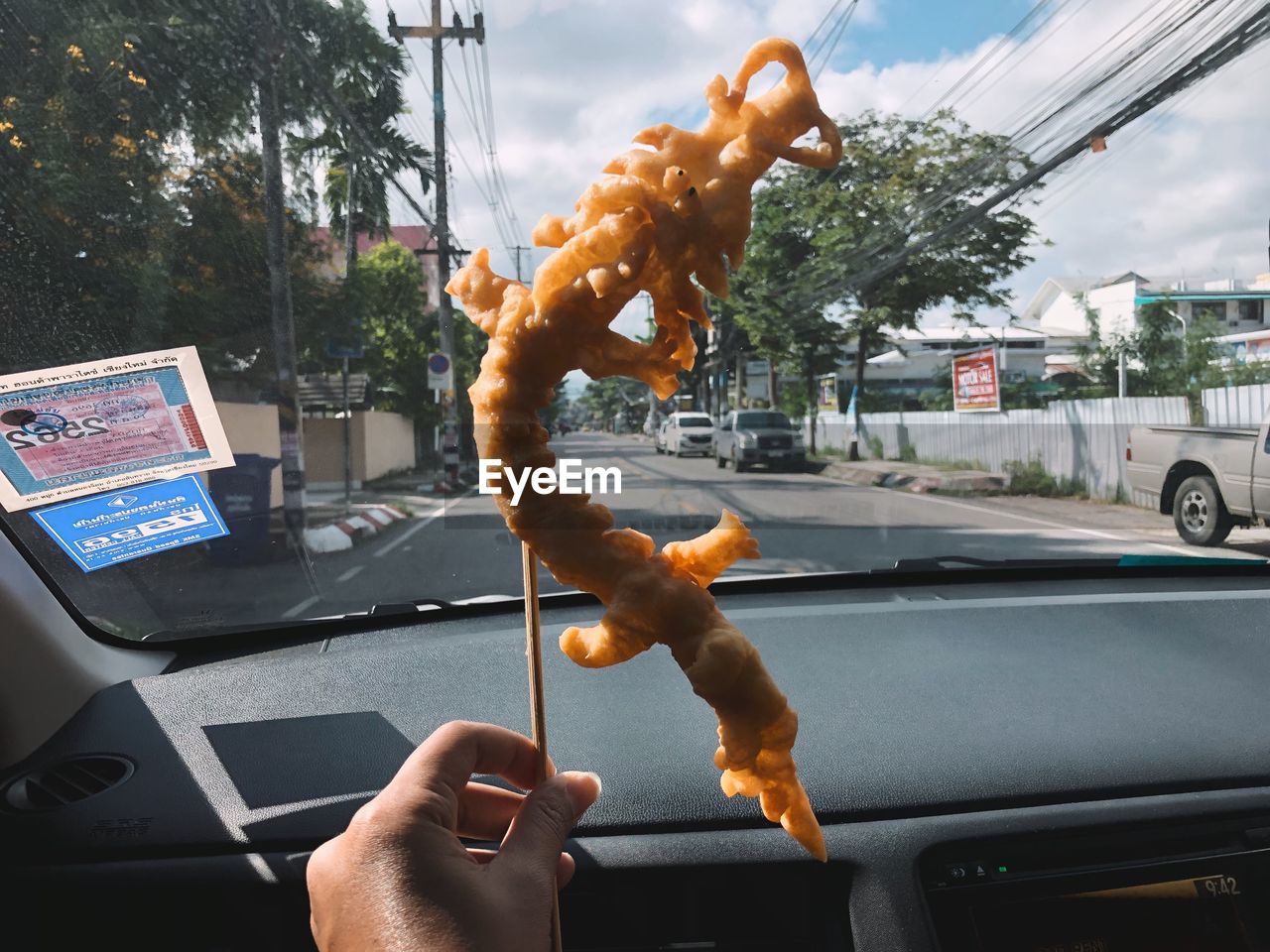 Cropped hand of person holding fried food in car