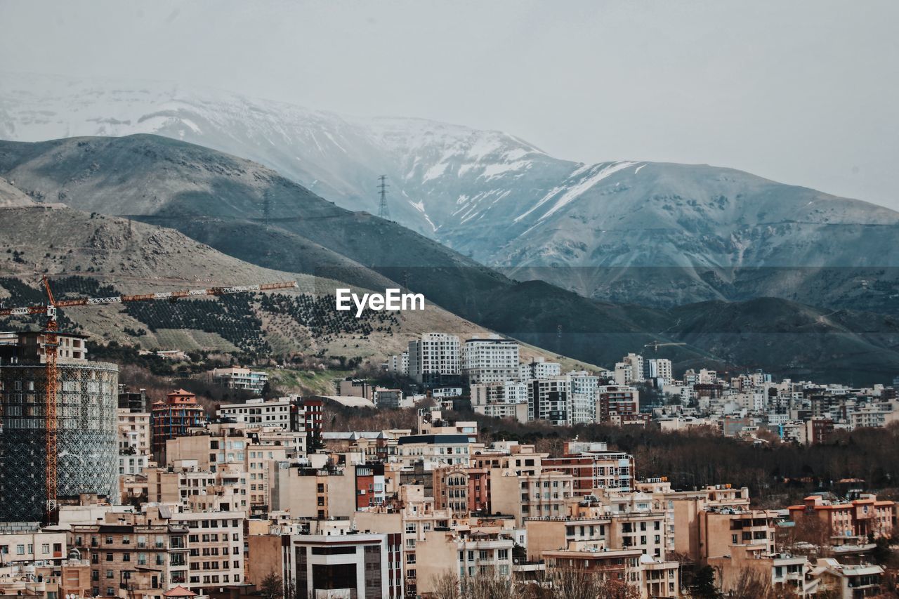 High angle view of buildings by alborz mountains against sky