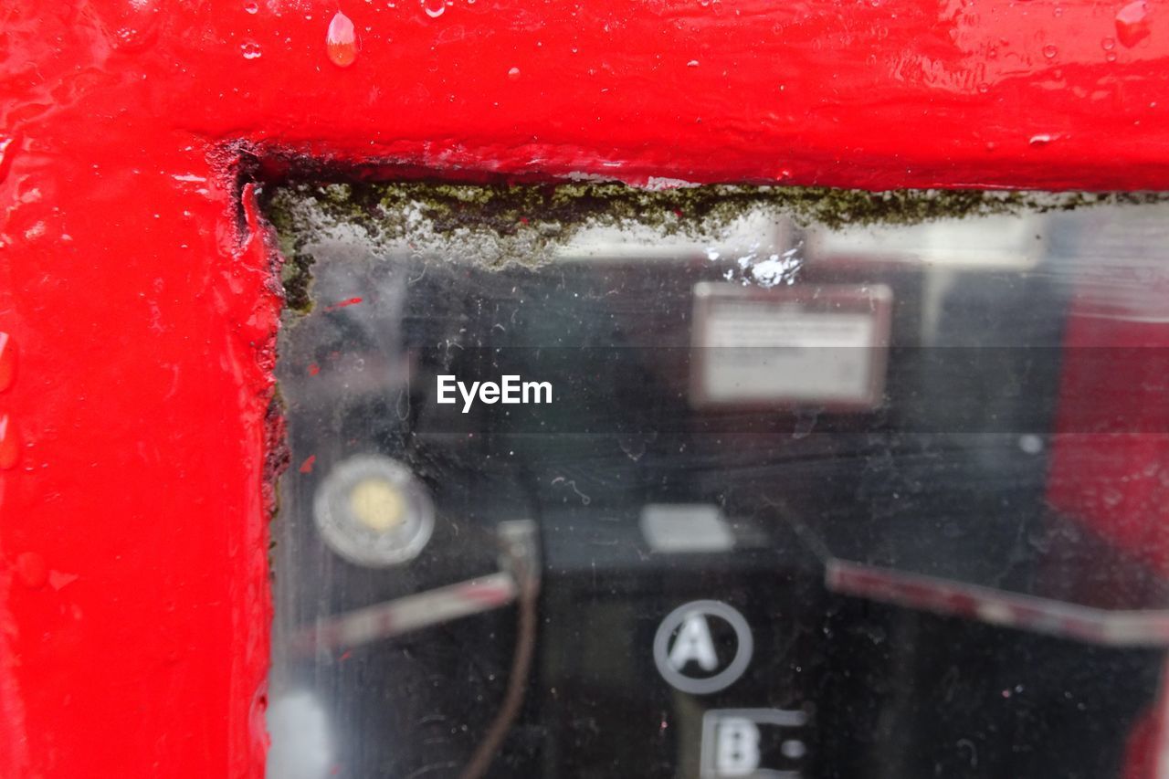 CLOSE-UP OF WET WINDOW WITH RED CAR