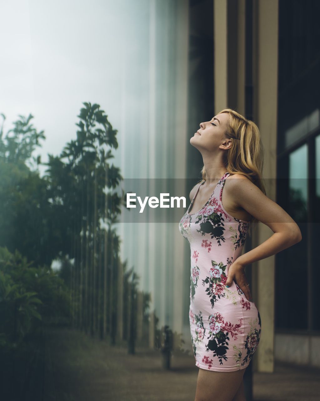 Side view of woman standing against trees against sky