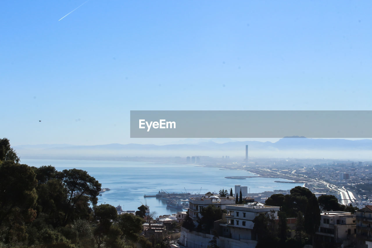 HIGH ANGLE VIEW OF CITY BUILDINGS AGAINST CLEAR SKY