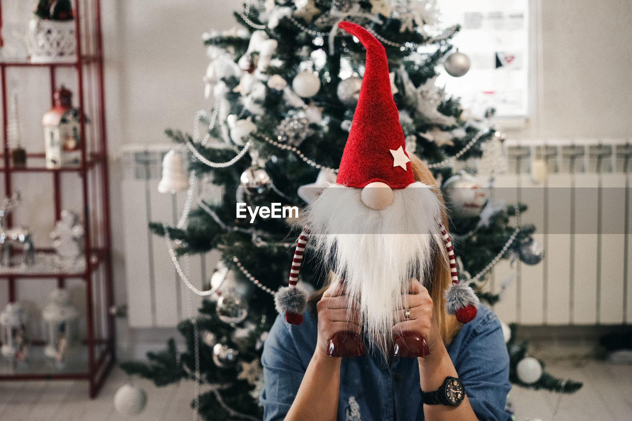 Woman hiding behind christmas toy at home