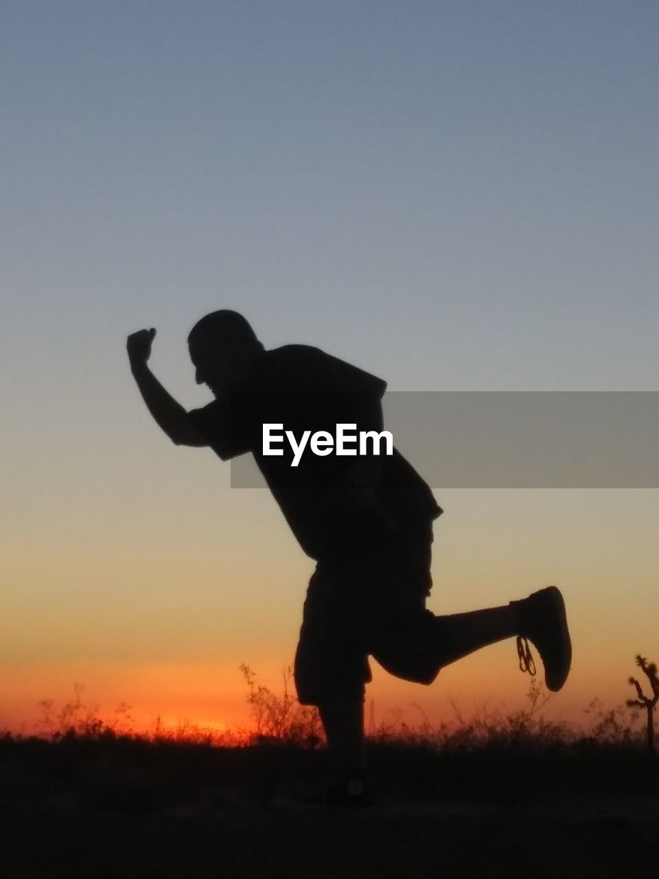 Silhouette man running on field against sky during sunset