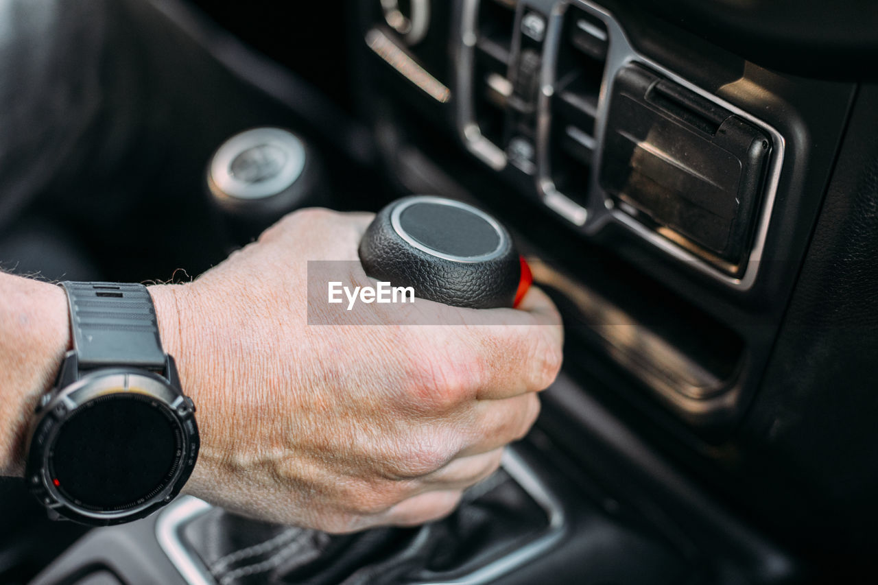 Crop view of anonymous man with her hand on the gear shift of an off-road car