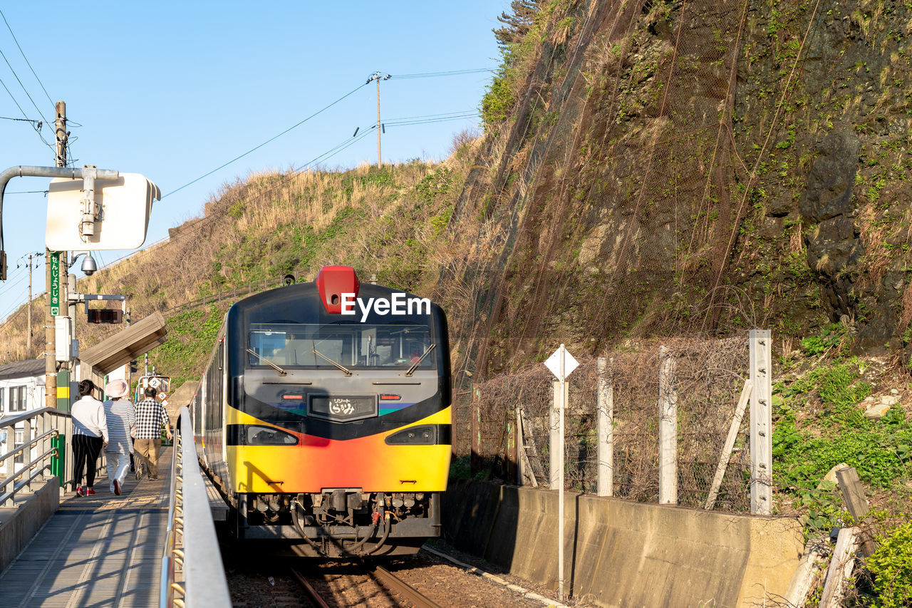 TRAIN ON RAILROAD TRACK BY MOUNTAINS AGAINST SKY