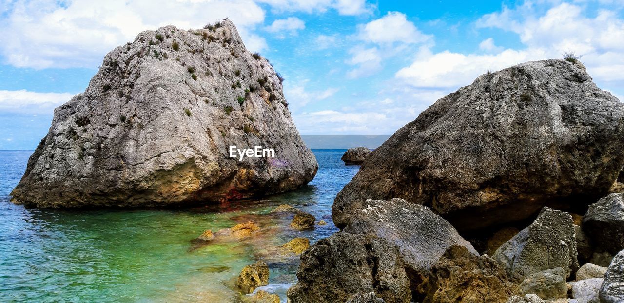 Rock formation in sea against sky