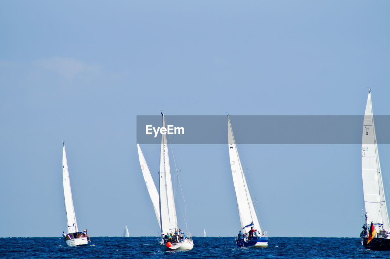 Sailboats on sea against clear blue sky